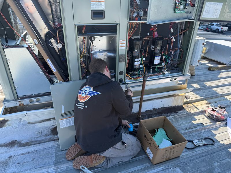 Air Support technician repairing compressors on a commercial rooftop HVAC unit